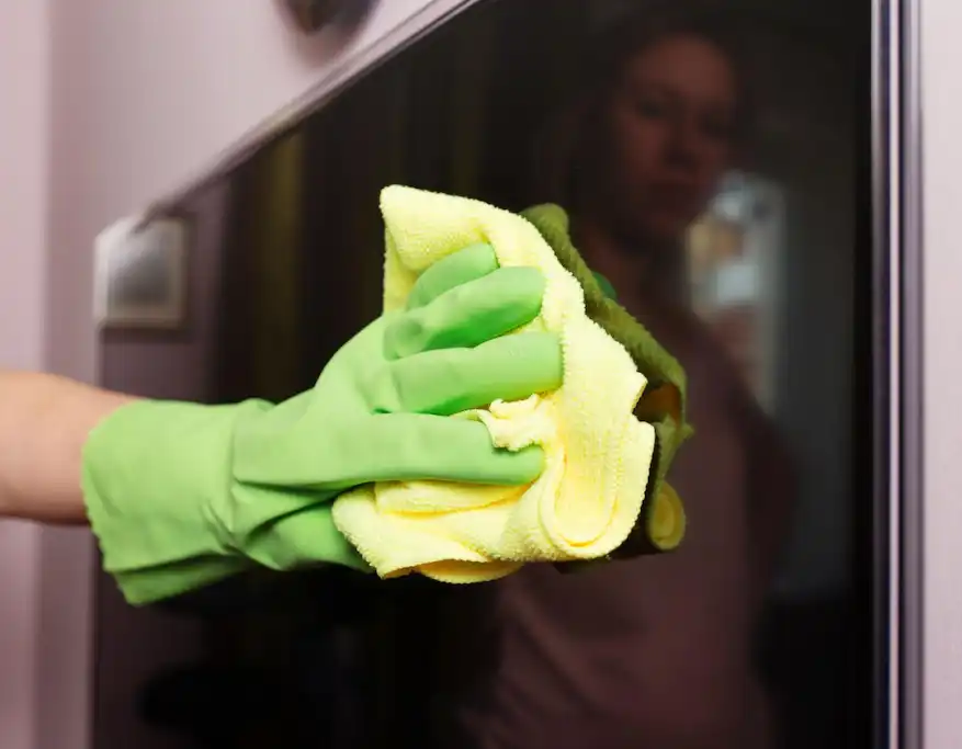 Hand wiping an LCD screen with a blue microfiber cloth – How to Clean an LCD Screen Safely.