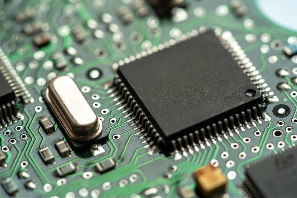 Microcontroller integrated circuit on a green PCB, showing detailed circuit paths and embedded electronic components. 